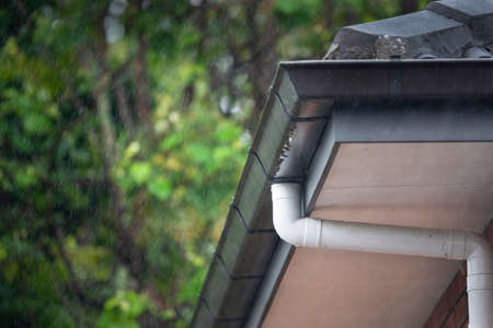 Roof gutter and downpipes in the rain with visible raindropsの写真素材