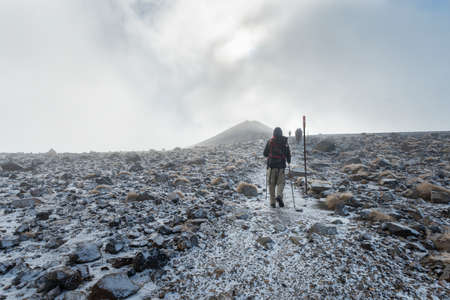 Hiking the steep scree terrain to the Red Crater in the heavy fog on Tongariro Alpine Crossing. New Zealand.の写真素材