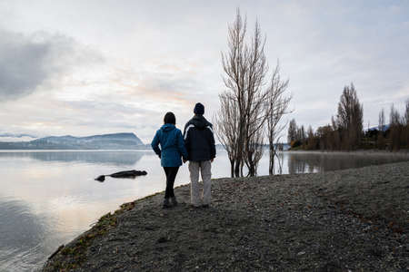 Couple standing on the shore of Lake Wanaka in winter, South Island.の写真素材