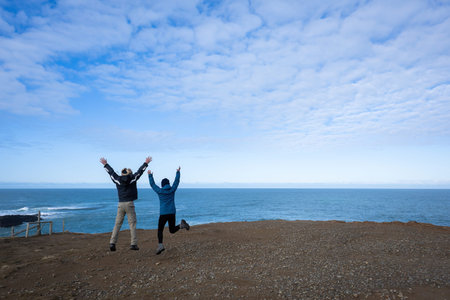 Senior couple jumping at the Slope Point, southernmost point of South Island, New Zealand.の写真素材
