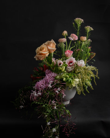 Flowers in basket against a black background, vertical format.の写真素材