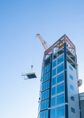 Apartment under construction. Crane lifting building materials up. Auckland. Vertical format.の写真素材