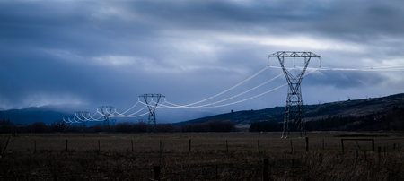 Pylons and power cables under stormy dark clouds, Central Otago, South Island.の写真素材