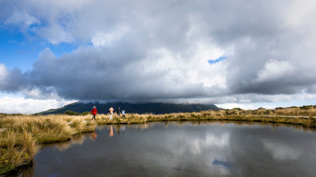 Four people hiking Pouakai Tarn. Mt Taranaki in the thick clouds. Taranaki. New Zealand.の写真素材