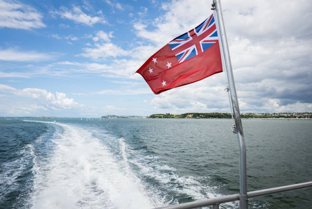 The New Zealand red ensign, also known as âthe red dusterâ flies on the boat cruising Hauraki Gulf. New Zealand.の写真素材