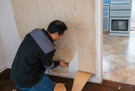 Man removing wallpaper inside an old house. Home interior renovation project.の写真素材