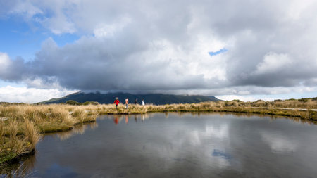 People hiking Pouakai Tarn. Mt Taranaki in the thick clouds. Taranaki. New Zealand.の写真素材
