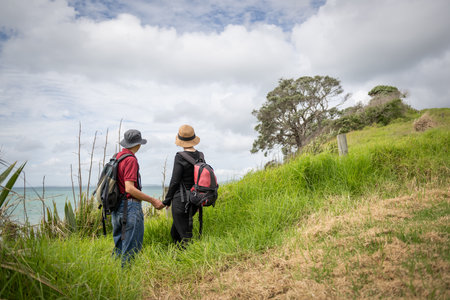 Couple holding hands, enjoying stunning views of Hauraki Gulf. Long Bay coastal walk. Auckland.の写真素材