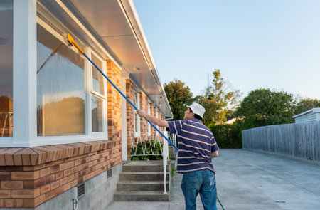 Man washing windows with long pole and brush. Home maintenance. Auckland.の写真素材