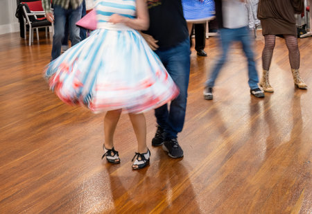 People enjoying dancing at a dance club. Motion blur of beautiful flying skirt captured in camera by...
