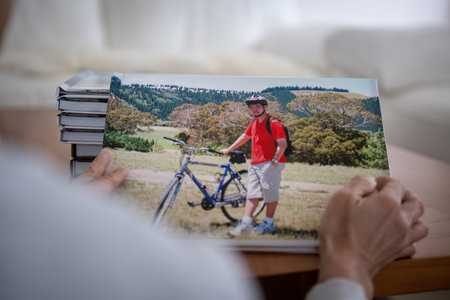 Woman looking at photobook of family holiday trip with piles of photo albums on coffee table.の写真素材