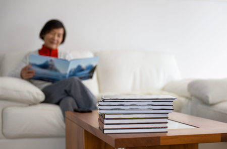 Woman smiling and holding family travel photo album. Selective focus on a pile of photobooks on...