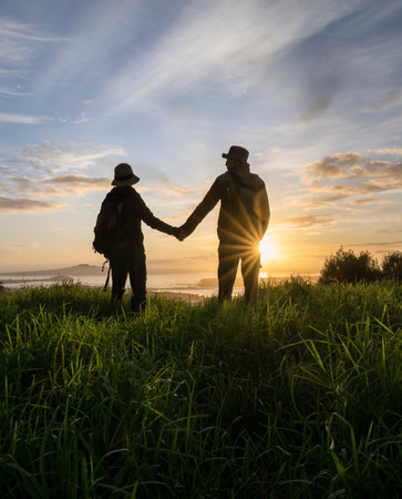 Couple standing on Mt Eden summit and looking at Rangitoto Island at sunrise. Auckland. Vertical format.の写真素材