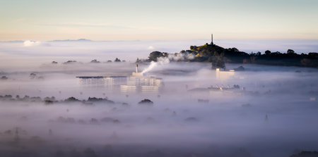 One Tree Hill above a sea of fog, view from Mt Eden summit. Smoke from a big building drifting over Auckland city.の写真素材