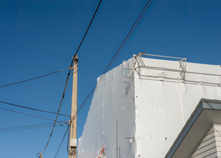 Residential house under repair with metal scaffolding and white sheet cover around it.の写真素材