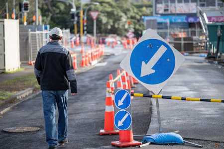 Man walking on the road with orange traffic cones diverting the traffic. Road under maintenance. Auckland.の写真素材