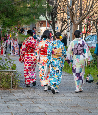Young women wearing traditional style of the Japan kimono walking on busy Kyoto street. Japan. Vertical format.の写真素材