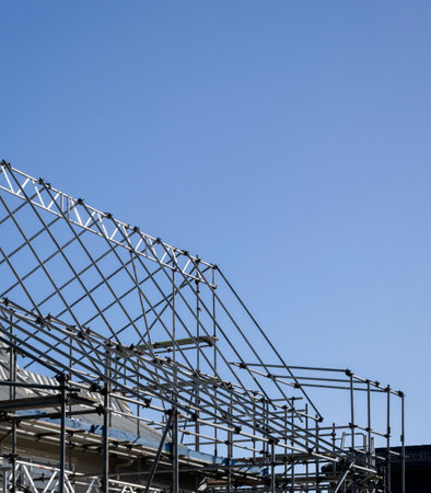 Residential house under repair with metal scaffolding around it, under a bright blue sky. Vertical format.の写真素材