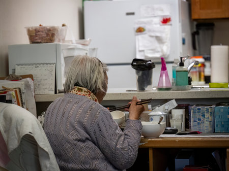 Senior woman eating dinner with chopsticks at home. Senior citizen living Independently.の写真素材