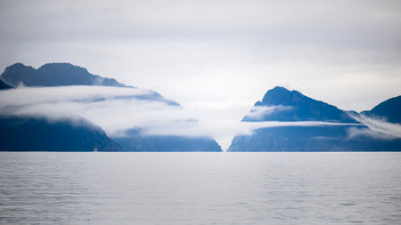 Clouds drifting around the mountains. A boat sailing in Resurrection Bay. Kenai Fjords National Park, Seward, USA.の写真素材