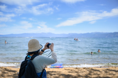 Woman taking photos of sunny Pope Beach using smartphone. Unrecognizable people enjoying themselves on the water. South Lake Tahoe.の写真素材