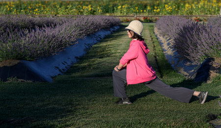 Woman doing stretch exercises in a lavender garden.の写真素材