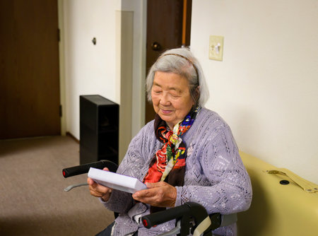 Senior woman holding a box inside the home, with a smile on her face.の写真素材