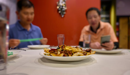 Stir-Fry dish on the table. Out-of-focus men talking and checking on smartphone.の写真素材