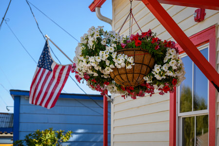 Beautiful flowers in a hanging basket and American flag flying outside the house. Poulsbo. Washington State.の写真素材