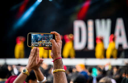 People taking photos of dance performances at the Diwali festival using smartphone. Selective focus...
