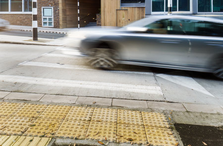 Grey car driving up speed bump and pedestrian crossing in Auckland.の写真素材