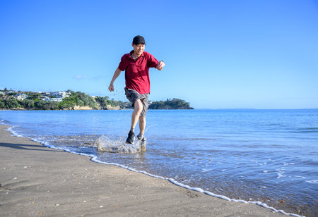 Man running in water on Milford Beach. Auckland.の写真素材