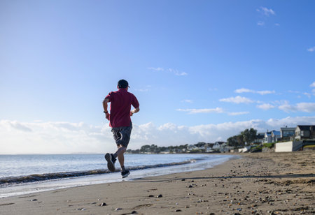 Man running on the beach in the morning. Milford beach. Auckland.の写真素材