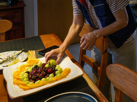 Woman preparing fruit platter on the dinner table. Home cooking and entertainment concept.の写真素材