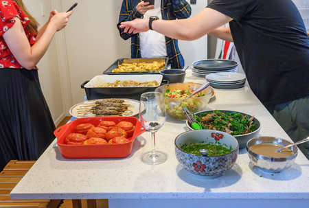 Young people holding smartphones taking photos of festival food on the kitchen benchtop. Home cooking and entertainment concept.の写真素材