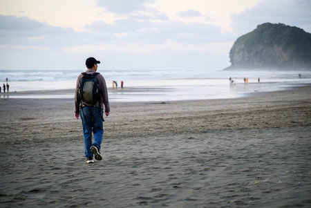 People walking and playing at Piha beach. Auckland.の写真素材