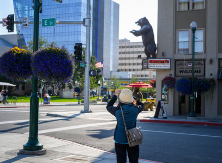Tourists taking photos of a grizzly bear statue using smartphones. Downtown Anchorage. Alaska.のeditorial素材