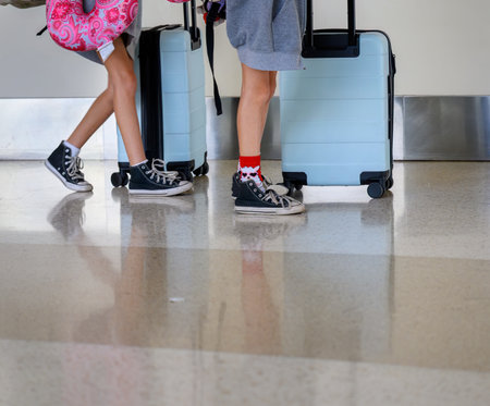 Legs of two teenagers walking with suitcases in the airport.の写真素材