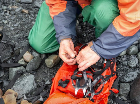 Hands packing up ice crampons after ice climbing.