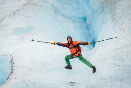 Man holding hiking poles and doing yoga poses in front of glacier crevasse. Exit Glacier. Kenai Fjords National Park. Alaska.の写真素材