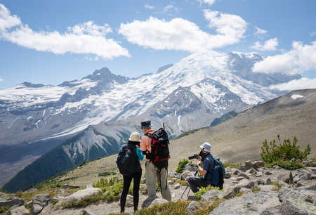 Three people hiking the Sunrise Trai. Mt Rainier in the background. Mt Rainier National Park. Washington State.の写真素材