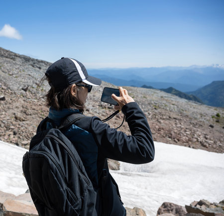 Woman taking photos using a smartphone at Skyline Trail. Mt Rainier National Park. Washington State.の写真素材