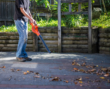 Man working with a leaf blower in the backyard.