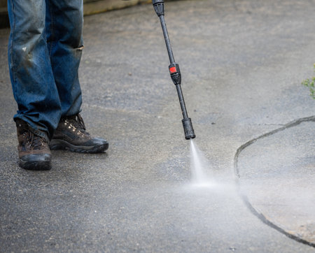 Worker cleaning pavement using an electric water blaster.の写真素材