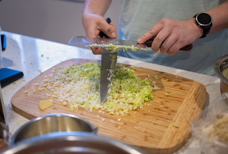 Hands of a man chopping cabbage using two knives in the home kitchen.の写真素材