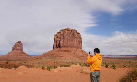 Young man taking photos of Merrick Butte using a smartphone. Monument Valley. Arizona. USA.の写真素材