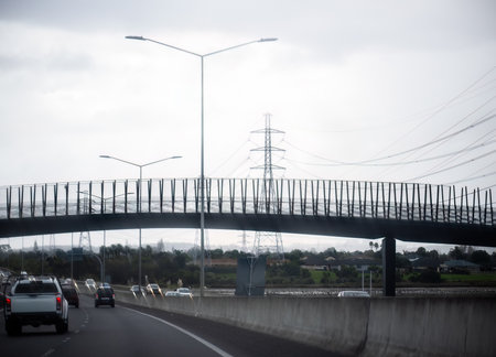 Transmission pylons and power lines along the motorway. Bridge across the motorway. Auckland.の写真素材