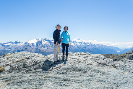 Couple standing on top of Conical Hill.  Hollyford Valley and Tasman Sea in the distance. Routeburn Track. South Island. New Zealand.の写真素材