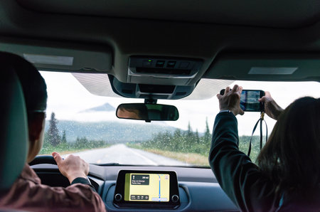 Couple driving in Denali National Park and Preserve in the rain. Passenger taking photos using a smartphone. Alaska. USA.の写真素材