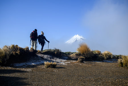 Couple looking at Snow-capped Mt Taranaki in the clouds. Pouakai Circuit track. New Zealand.の写真素材